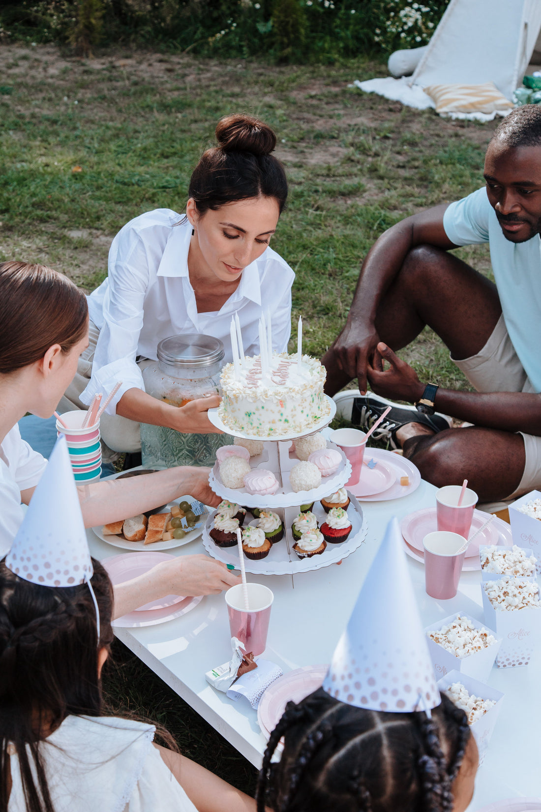 Guests gathered around a home birthday table with coordinated pink disposable plates and cups