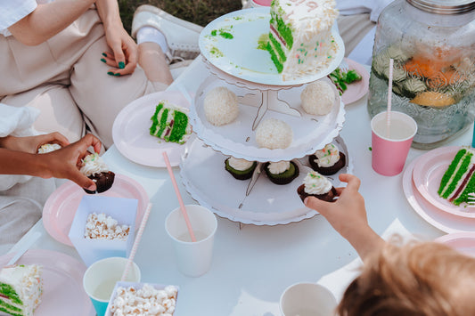 Family reaching for cupcakes on a tiered dessert stand at a garden birthday party