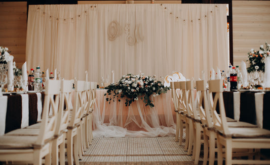 Elegant draped wedding reception backdrop with floral centerpiece and place settings