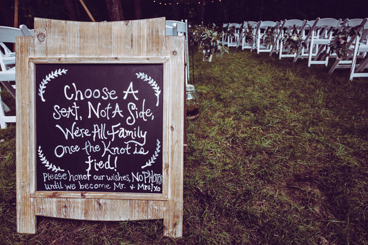 Wedding seating sign displayed near rows of ceremony chairs outdoors