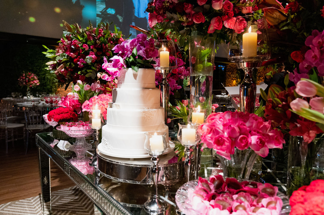 Tiered wedding cake styled with pink and purple floral arrangements and candles