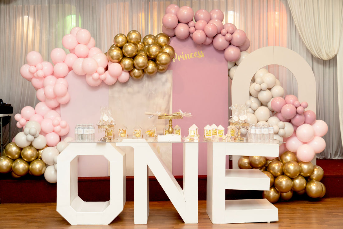 Party backdrop featuring metallic gold and soft pastel pink balloon garland zones
