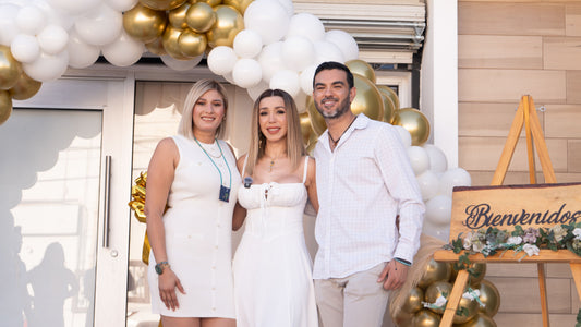 Guests smiling together beside a welcome sign on an easel with gold and white balloons