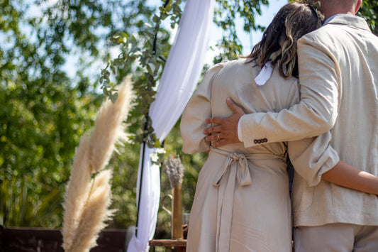 Couple embracing beneath a fabric-draped wedding ceremony arch outdoors