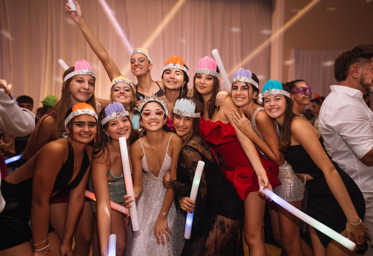 Group of friends celebrating at an evening party holding glowing foam favor sticks