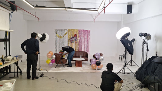 Crew adjusting a fringe photo backdrop and lighting before a party photoshoot