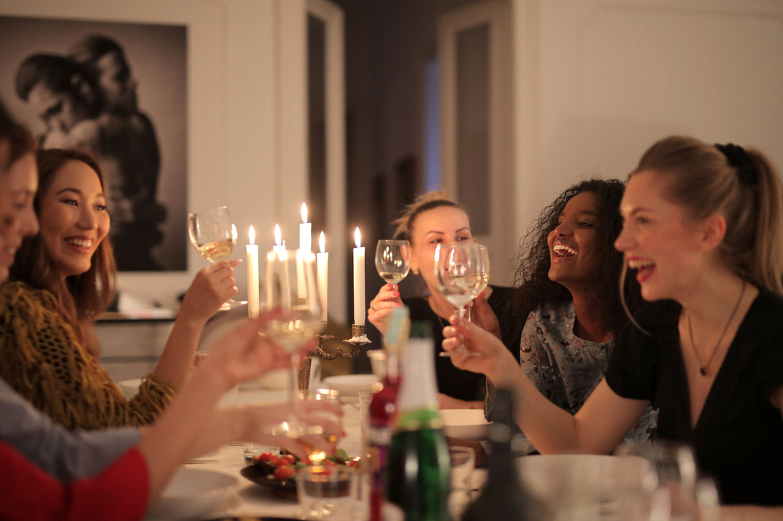 Friends laughing and toasting at a warm, candlelit home dinner party table