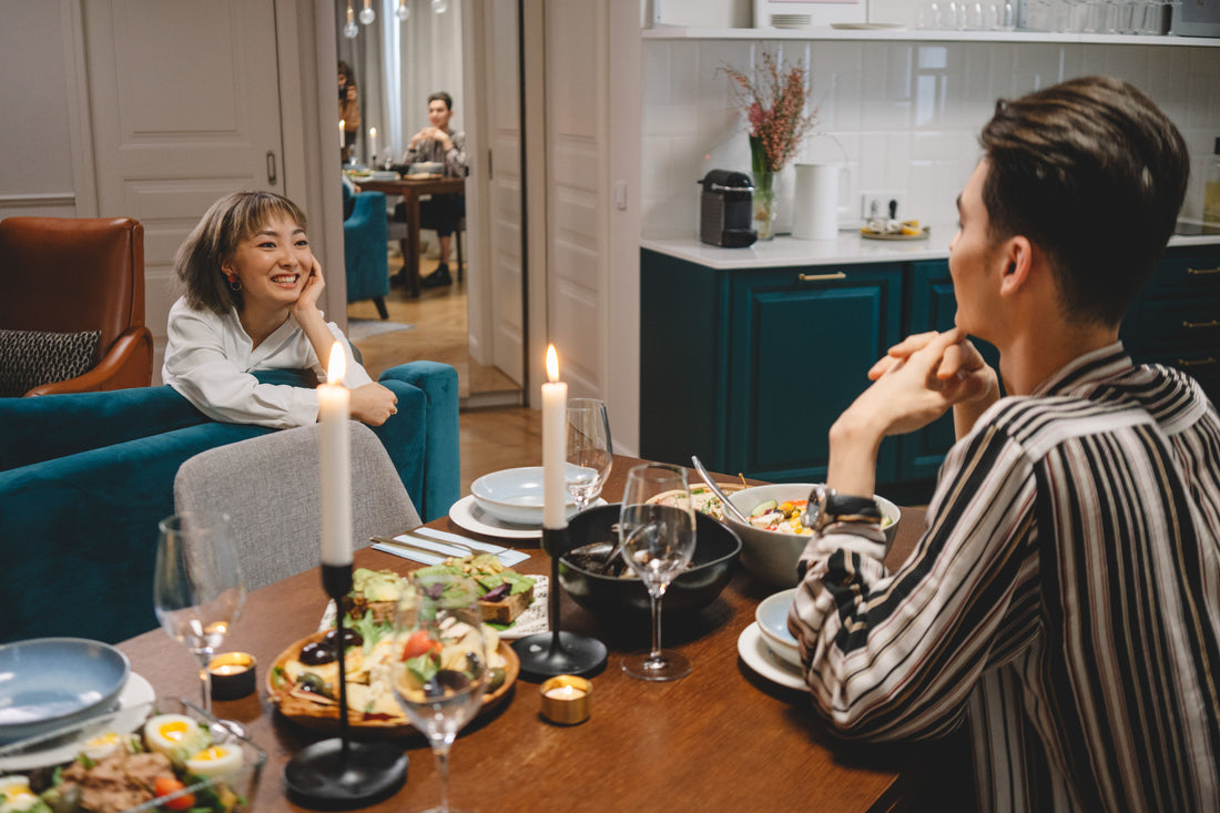 Friends conversing at a home dinner table decorated with low candle centerpieces