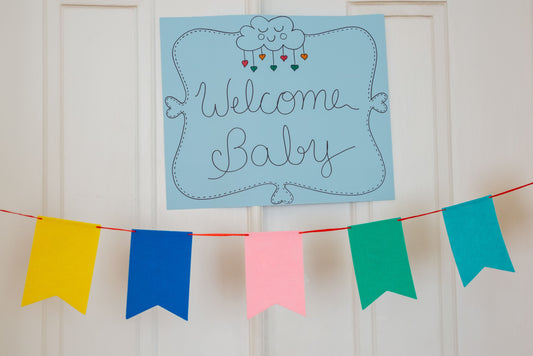 Welcome Baby sign with a colorful pennant banner displayed for a baby shower