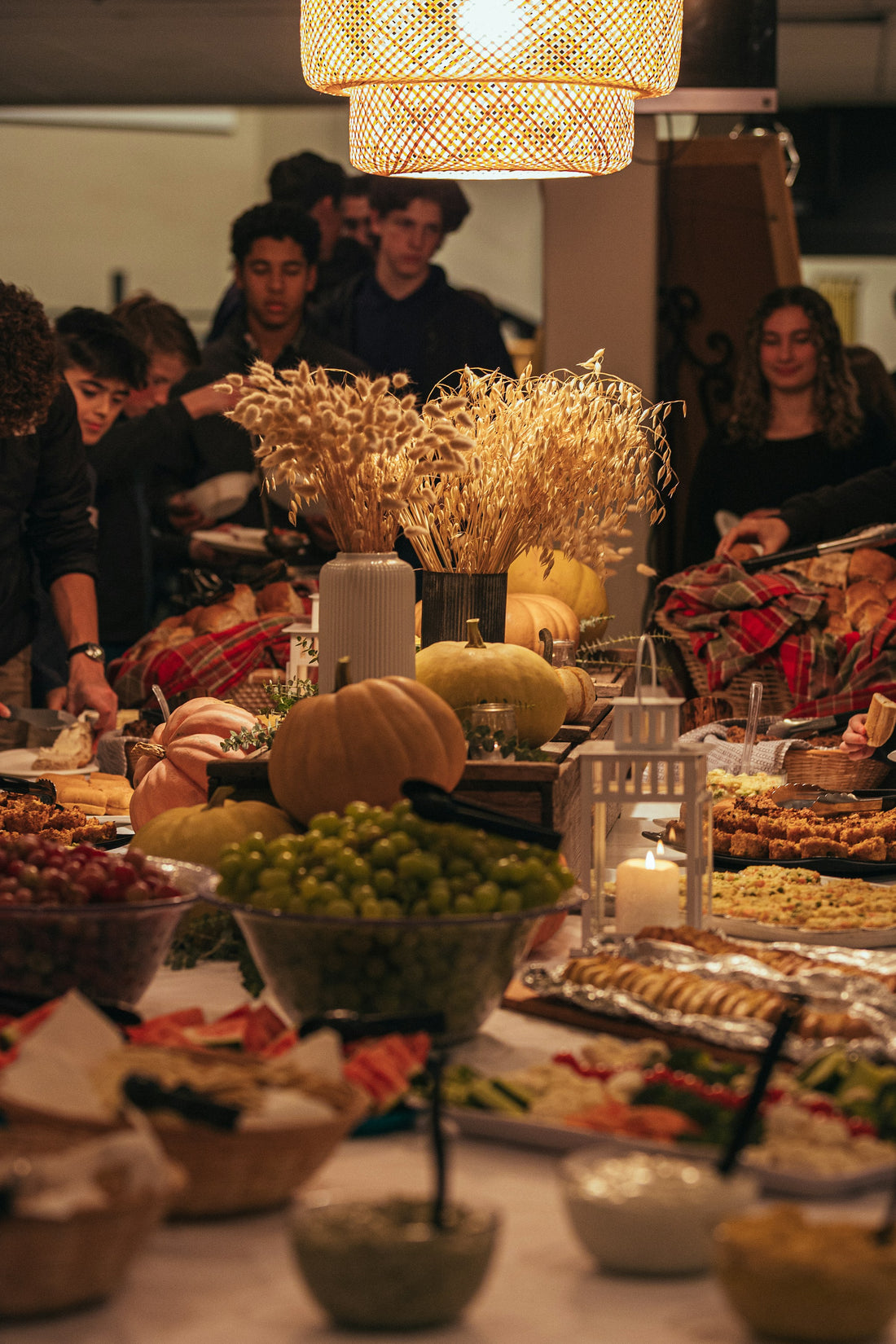 Warm autumn gathering with guests around a table styled in rust and wheat tones