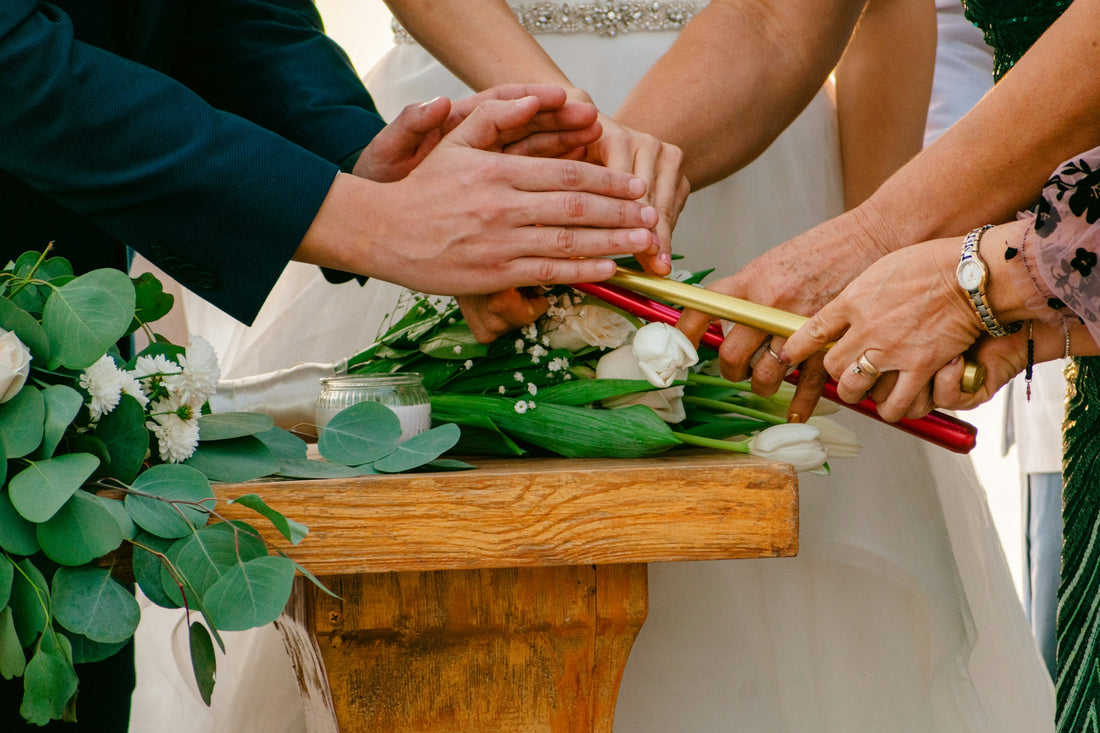 Hands lighting unity candles during an indoor wedding ceremony