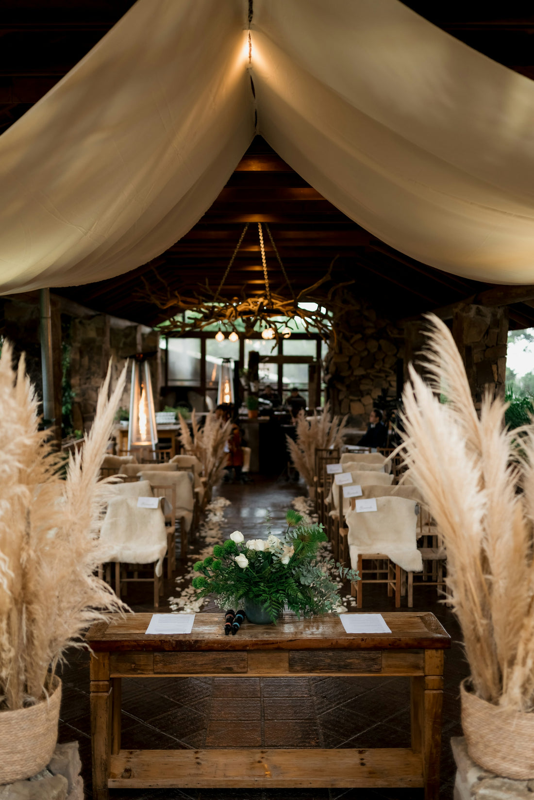 Rustic wedding venue aisle decorated with dried pampas grass and a fresh flower centerpiece